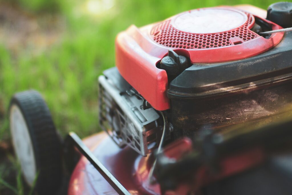 A red lawn mower sitting on top of a lush green field